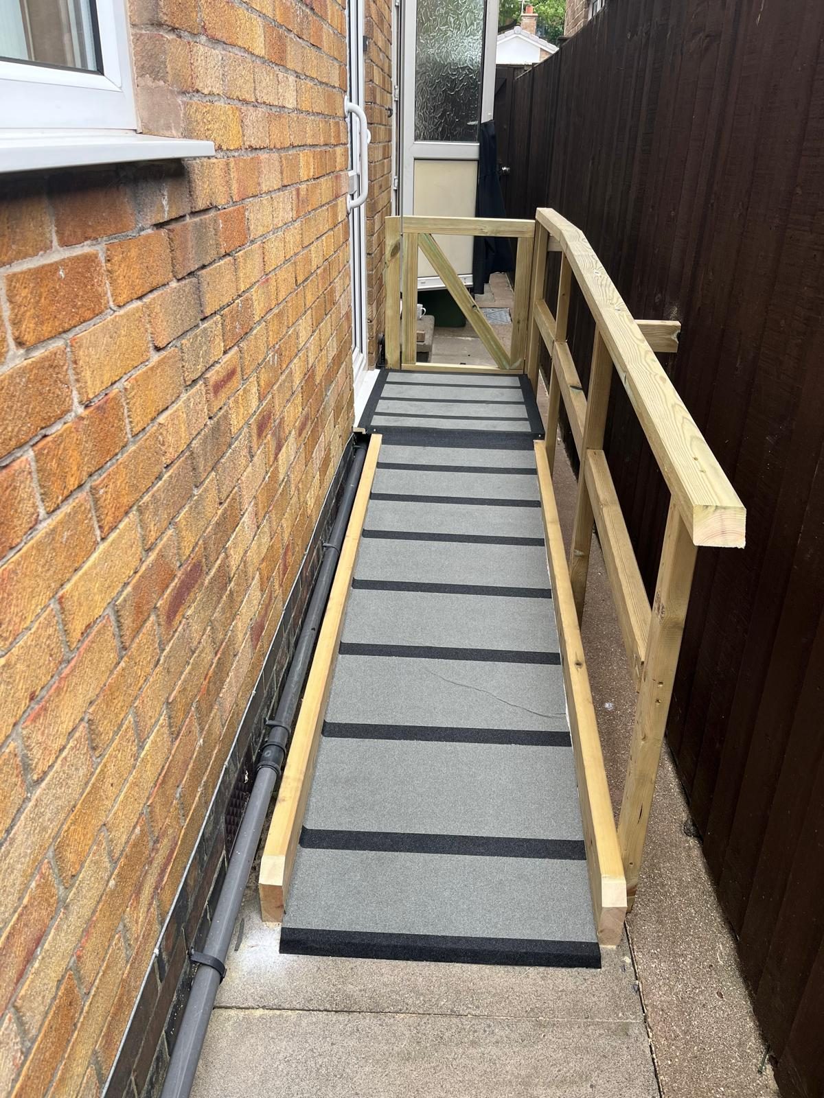 Timber access ramp with handrails and grip strips running to a back door
