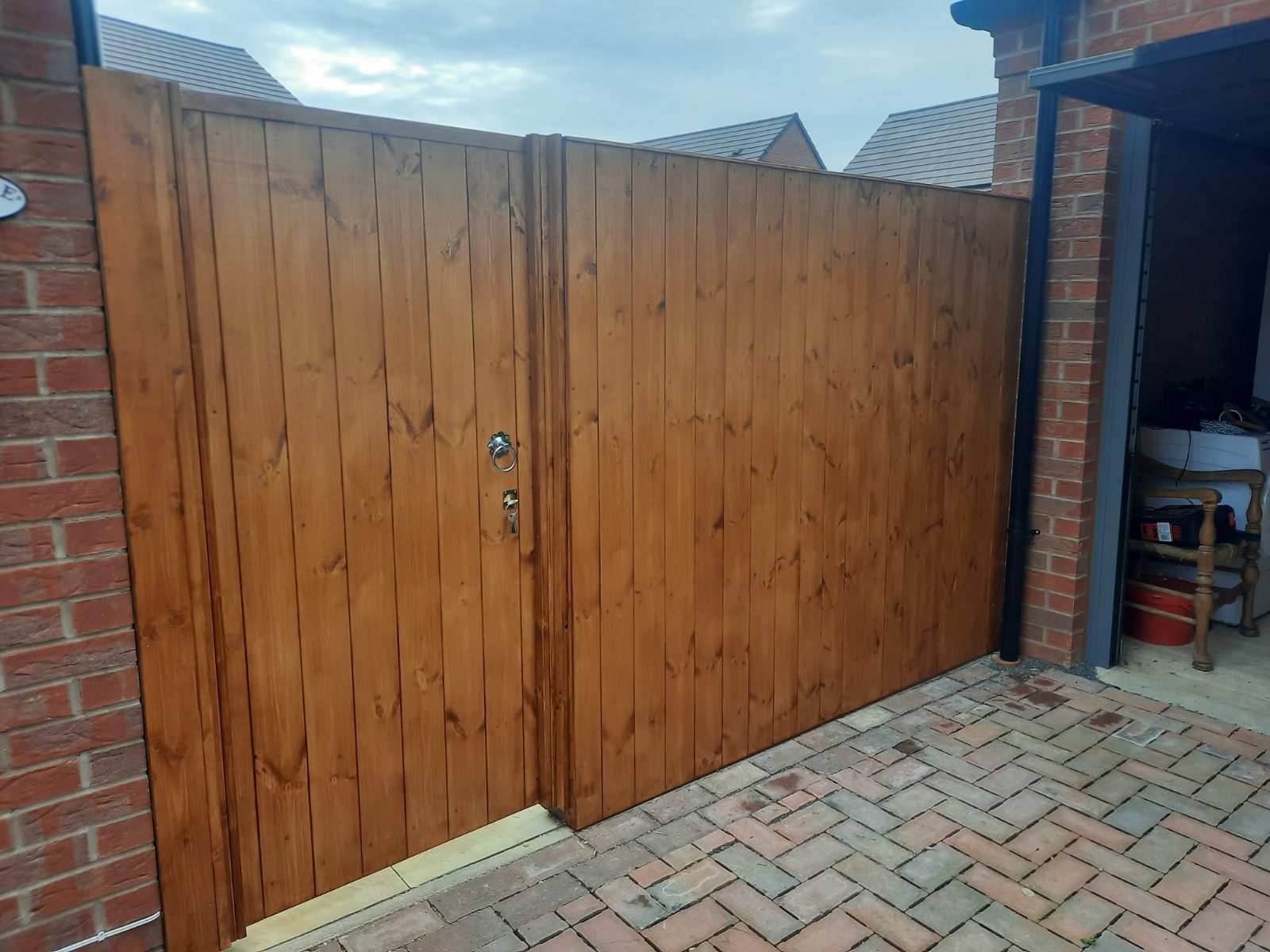 Tall pair of stained timber double gates closing off a side return