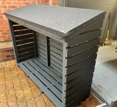 Painted slatted log store against a brick wall