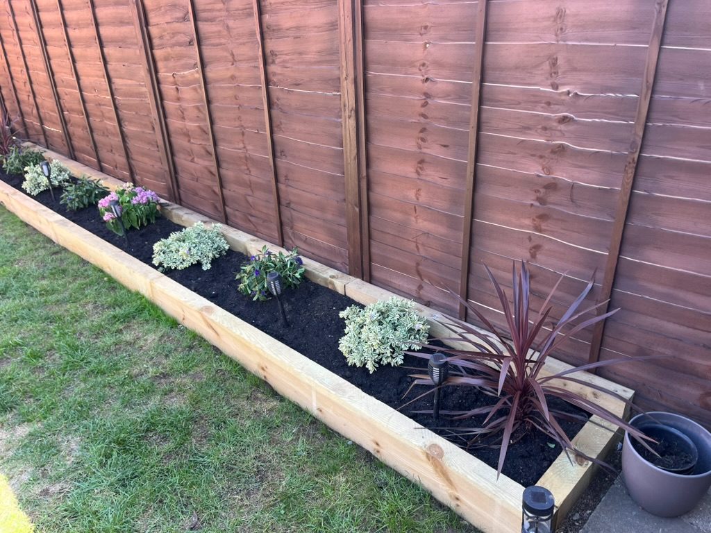 Newly built sleeper-edged border planted along a fence line