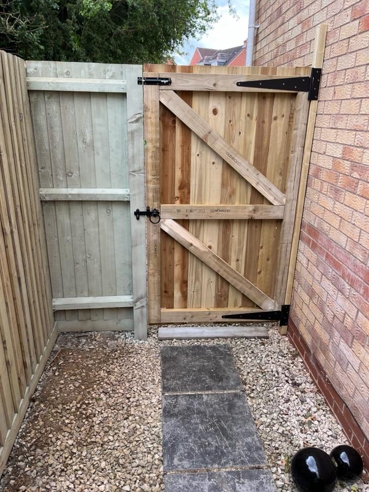 Braced and ledged timber gate on black strap hinges in a gravelled side return
