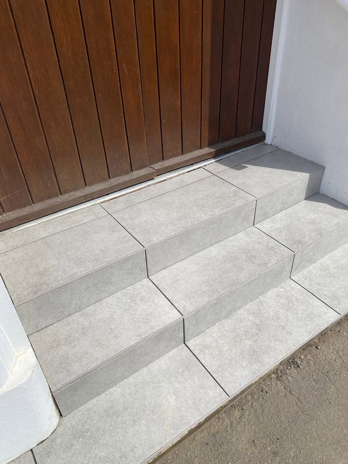 Doorstep rebuilt in pale porcelain tile with crisp nosings